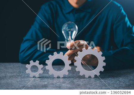 Light iDeas concept project business gear management manager devops process automation deploy, worker holding glowing bulb over gears for efficient workflow system progress 136032694