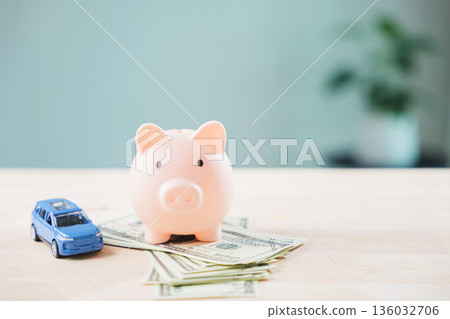 Piggy bank on money near car to save for auto insurance, fuel cost, refinance loan, finance, gas to drive, transportation, routine vehicle maintenance or monthly expenses Piggy bank on money near car to save for auto insurance, fuel cost, refinance loan, finance, gas to drive, transportation, routine vehicle maintenance or monthly expenses 136032706