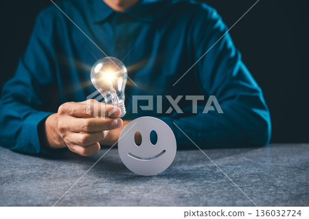 Customer experience satisfaction rating shows employee holding glowing light bulb beside happy smiley face icon representing excellent service feedback for business success 136032724