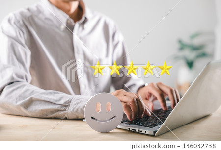 Positive customer feedback evaluation, person uses laptop for online survey, giving 5 star rating for excellent service experience, showing happy client satisfaction with business quality 136032738