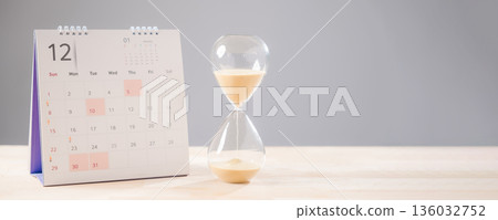 Hourglass illustrates time passing, sand flows quickly, calendar shows important schedule, job deadline approaches, work planning essential for career, glass hour countdown indicates wait passes Hourglass illustrates time passing, sand flows quickly, calendar shows important schedule, job deadline approaches, work planning essential for career, glass hour countdown indicates wait passes 136032752
