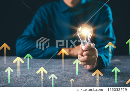 Hand holding light bulb moment lightbulb idea innovation business background concept power digital inspiration shows colorful rising arrows for growth success and development 136032759