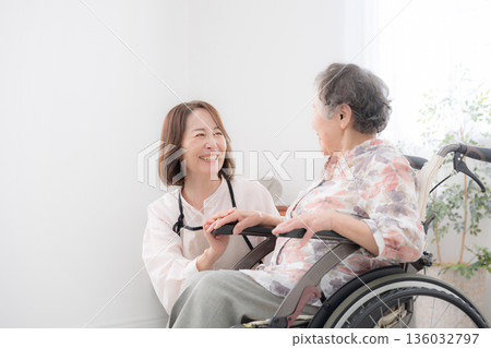 Caring for a wheelchair-bound mother at home, looking into each other's eyes as they talk 136032797