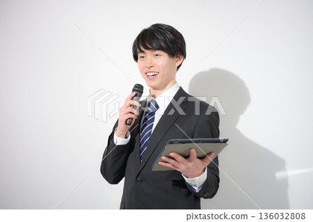 一位商人手持麥克風，正在進行演講、主持採訪或接受採訪。 136032808
