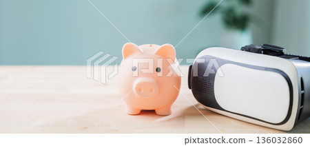 Pink piggy bank, money, metaverse banking, casino vr, ar and saving features represent digital finance concepts on wooden table with virtual reality headset near bright green plant Pink piggy bank, money, metaverse banking, casino vr, ar and saving features represent digital finance concepts on wooden table with virtual reality headset near bright green plant 136032860
