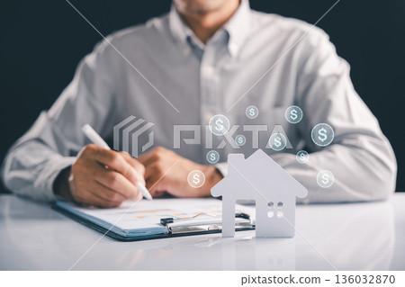 Property purchase and sales agreement being signed while a broker presents detail on a house model representing financial growth for sale rental and investment opportunities, value of this property 136032870