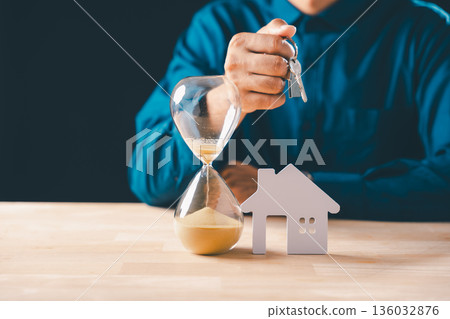 Sand filled hourglass shows time running out for real estate deal, man holds keys to new house, mortgage property concept, home buying deadline fast approaching for building acquisition Sand filled hourglass shows time running out for real estate deal, man holds keys to new house, mortgage property concept, home buying deadline fast approaching for building acquisition 136032876