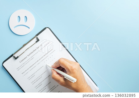 Customer survey form for feedback on clipboard, hand writing satisfaction review with pen, business checklist for data collection, sad face suggests negative experience evaluation Customer survey form for feedback on clipboard, hand writing satisfaction review with pen, business checklist for data collection, sad face suggests negative experience evaluation 136032895