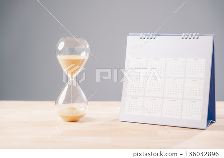 Time hourglass, sand slowly passing, calendar for scheduling important deadlines, work planning, career advancement, job search timeline, future goals, professional development strategy 136032896