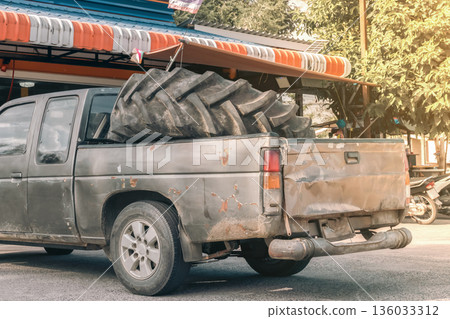 repair of agricultural tires and tires for special equipment. A large tire from a grader in the back of an old rusty pickup truck on Koh kho khao Island in Thailand. High quality photo 136033312