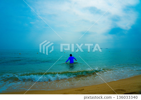 Asian man entering the sea Asian man entering the sea 136033340