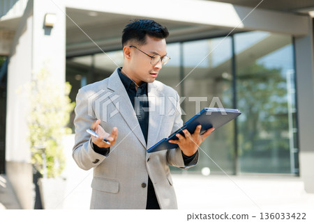 Focused businessman planning new goals and writing business ideas in notebook outdoors, symbolizing motivation, success, and fresh start in professional life. Focused businessman planning new goals and writing business ideas in notebook outdoors, symbolizing motivation, success, and fresh start in professional life. 136033422