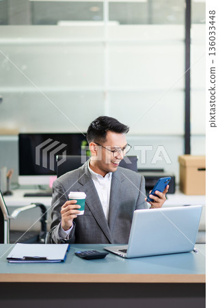 Asian man using laptop and tablet while sitting at her working place. Concentrated at work. Asian man using laptop and tablet while sitting at her working place. Concentrated at work. 136033448