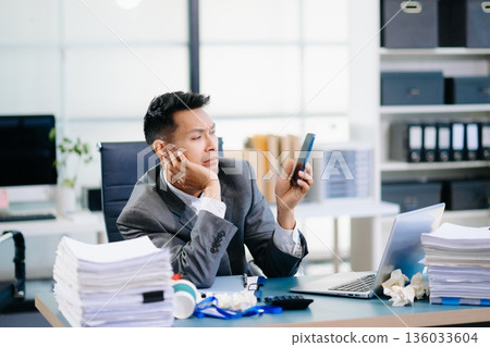 Professional office worker managing phone call and report review simultaneously, showing multitasking and corporate efficiency. Professional office worker managing phone call and report review simultaneously, showing multitasking and corporate efficiency. 136033604