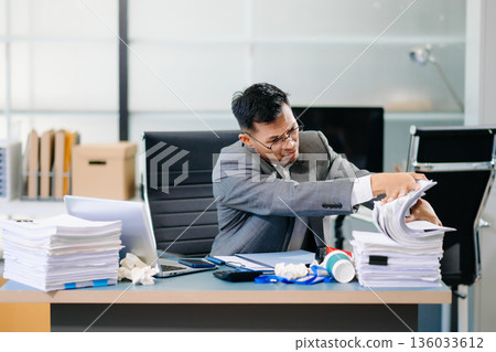 Focused office worker analyzing documents, reviewing business reports with stress and concentration in workplace setting. Focused office worker analyzing documents, reviewing business reports with stress and concentration in workplace setting. 136033612