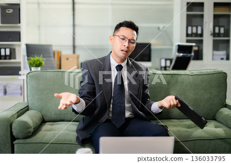 Confused businessman stressed while working on laptop and tablet in modern office, business problem, financial loss, pressure, failure, decision making and work challenge. Confused businessman stressed while working on laptop and tablet in modern office, business problem, financial loss, pressure, failure, decision making and work challenge. 136033795