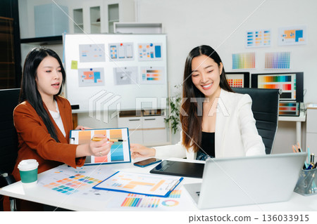 Two female designers collaborating on color palette and UX UI project in a modern creative office. Perfect for business, teamwork, and innovation themes. Two female designers collaborating on color palette and UX UI project in a modern creative office. Perfect for business, teamwork, and innovation themes. 136033915