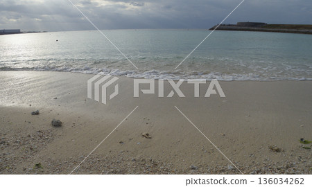 陰天的傍晚,宜野灣熱帶海灘平靜的海面 陰天的傍晚,宜野灣熱帶海灘平靜的海面 136034262
