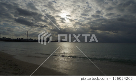 陰天的傍晚,宜野灣熱帶海灘平靜的海面 陰天的傍晚,宜野灣熱帶海灘平靜的海面 136034263