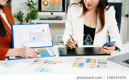 Creative female designers team using pen tablet and color palette working in graphic design Choose colors for working on tablets and computer designs. 136034304