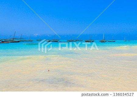 View of tropical sandy Nungwi beach and traditional wooden dhow boats in the Indian ocean on Zanzibar, Tanzania View of tropical sandy Nungwi beach and traditional wooden dhow boats in the Indian ocean on Zanzibar, Tanzania 136034527