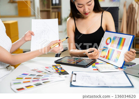 Fashion designers collaborating with color palettes, sketches, and digital tools in a studio. Creative design process, branding, textile planning 136034620