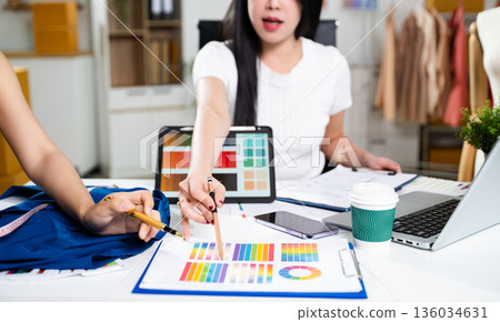 Fashion designers working together with fabric and color palette on digital tablet. Creative teamwork, textile planning and modern fashion studio concept Fashion designers working together with fabric and color palette on digital tablet. Creative teamwork, textile planning and modern fashion studio concept 136034631