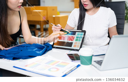 Fashion designers working together with fabric and color palette on digital tablet. Creative teamwork, textile planning and modern fashion studio concept Fashion designers working together with fabric and color palette on digital tablet. Creative teamwork, textile planning and modern fashion studio concept 136034632