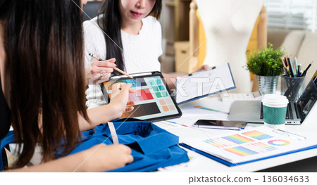 Fashion designers working together with fabric and color palette on digital tablet. Creative teamwork, textile planning and modern fashion studio concept Fashion designers working together with fabric and color palette on digital tablet. Creative teamwork, textile planning and modern fashion studio concept 136034633