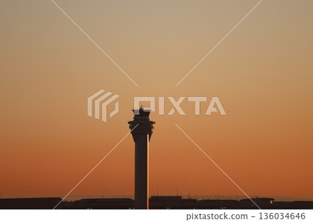 A landscape of a gradational sunrise sky, a silhouette of a control tower and buildings, and a hazy sea A landscape of a gradational sunrise sky, a silhouette of a control tower and buildings, and a hazy sea 136034646