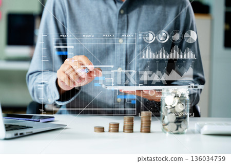 saving money with hand putting coins in jug glass and calculator to calculate budget concept finance and accounting saving money with hand putting coins in jug glass and calculator to calculate budget concept finance and accounting 136034759