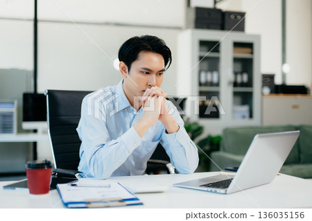 Asian businessman is stressed, bored, and overthinking from working on a tablet at the modern office. Asian businessman is stressed, bored, and overthinking from working on a tablet at the modern office. 136035156