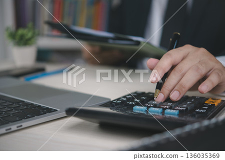 Business executive working with calculator, pen and document file, accounting service, financial management, tax report, company budget planning, audit process and economic analysis. Business executive working with calculator, pen and document file, accounting service, financial management, tax report, company budget planning, audit process and economic analysis. 136035369
