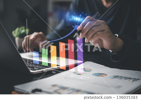 Man working on financial data with laptop and futuristic growth chart pointing at 2026, concept of business forecasting, planning, and digital finance strategy. 136035383