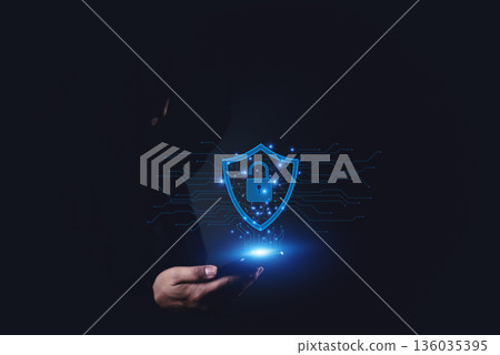 Cybersecurity visualization with hand holding smartphone and glowing shield lock, concept of mobile security, data privacy, protection, and safe digital connection. Cybersecurity visualization with hand holding smartphone and glowing shield lock, concept of mobile security, data privacy, protection, and safe digital connection. 136035395