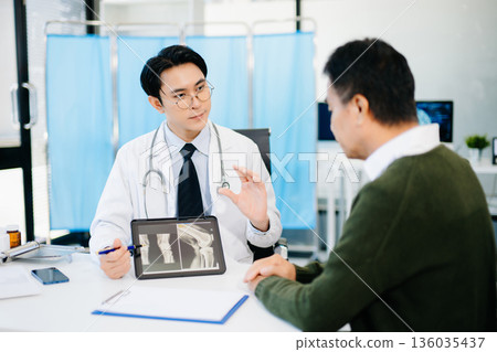 Doctor explaining knee X-ray results to patient in clinic, symbolizing orthopedic diagnosis, treatment, and modern healthcare consultation. Doctor explaining knee X-ray results to patient in clinic, symbolizing orthopedic diagnosis, treatment, and modern healthcare consultation. 136035437