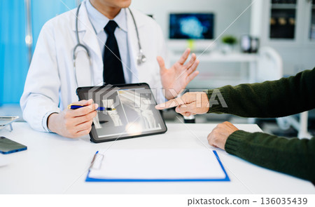 Doctor showing and explaining bone X-ray results to patient during medical consultation. Ideal for healthcare, orthopedic Doctor showing and explaining bone X-ray results to patient during medical consultation. Ideal for healthcare, orthopedic 136035439