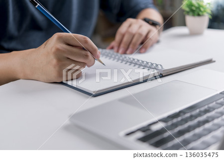 person writing in a notebook with a pencil. concepts of online education, planning, study, and the importance of written documentation and ideas. person writing in a notebook with a pencil. concepts of online education, planning, study, and the importance of written documentation and ideas. 136035475