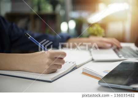 person studying and working at a desk, educational books and a laptop. modern learning and productivity, concepts of student life, online education, and career development. person studying and working at a desk, educational books and a laptop. modern learning and productivity, concepts of student life, online education, and career development. 136035482