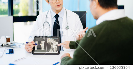 Doctor explaining knee X-ray results to patient in clinic, symbolizing orthopedic diagnosis, treatment, and modern healthcare consultation. Doctor explaining knee X-ray results to patient in clinic, symbolizing orthopedic diagnosis, treatment, and modern healthcare consultation. 136035504