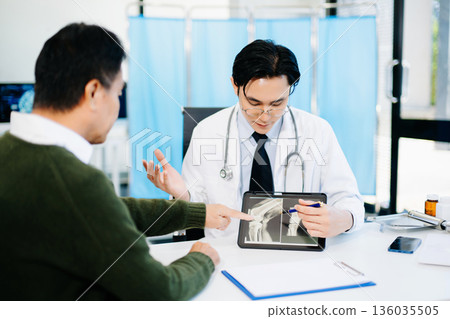 Doctor reviewing knee X-ray with patient in clinic, symbolizing orthopedic diagnosis, treatment 136035505
