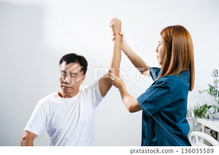 Female physiotherapist supports arm movement exercise for senior male patient during rehabilitation. Elderly care Female physiotherapist supports arm movement exercise for senior male patient during rehabilitation. Elderly care 136035589