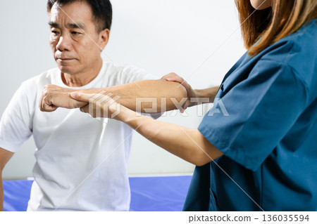 Female physiotherapist supports arm movement exercise for senior male patient during rehabilitation. Elderly care Female physiotherapist supports arm movement exercise for senior male patient during rehabilitation. Elderly care 136035594