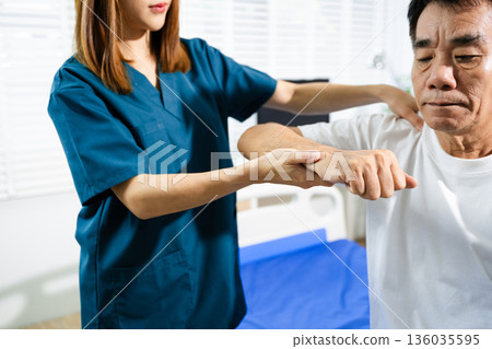 Female physiotherapist supports arm movement exercise for senior male patient during rehabilitation. Elderly care Female physiotherapist supports arm movement exercise for senior male patient during rehabilitation. Elderly care 136035595