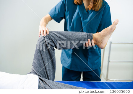 Female physiotherapist performs leg and knee therapy for patient during rehab session. Medical care, flexibility recovery Female physiotherapist performs leg and knee therapy for patient during rehab session. Medical care, flexibility recovery 136035600