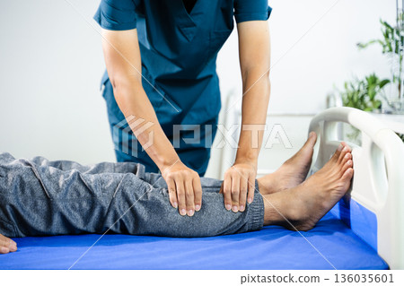 Physiotherapist assists patient with leg and ankle movement therapy during recovery session. Medical care, mobility training, and muscle rehabilitation Physiotherapist assists patient with leg and ankle movement therapy during recovery session. Medical care, mobility training, and muscle rehabilitation 136035601