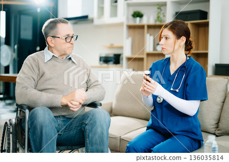 A professional nurse in blue uniform consults with a senior wheelchair patient at home, showcasing real people, empathy, and quality medical care A professional nurse in blue uniform consults with a senior wheelchair patient at home, showcasing real people, empathy, and quality medical care 136035814