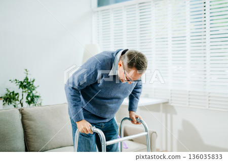 A senior man practices mobility with a walker during rehab, then celebrates progress with thumbs up, showcasing real people 136035833