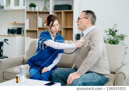 Elderly man receives home healthcare checkup as nurse uses stethoscope with care and professionalism. Medical, support Elderly man receives home healthcare checkup as nurse uses stethoscope with care and professionalism. Medical, support 136035852