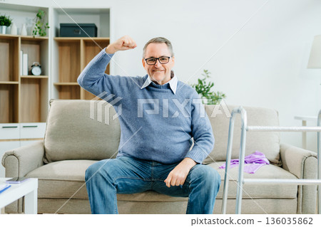 A senior man flexes his arms in celebration of rehabilitation success at home, showcasing strength, independence, wellness A senior man flexes his arms in celebration of rehabilitation success at home, showcasing strength, independence, wellness 136035862